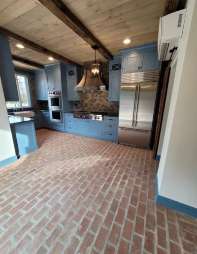 A kitchen with blue cabinets and a brick floor.