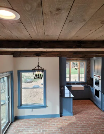 A kitchen with wood beams and a brick floor.