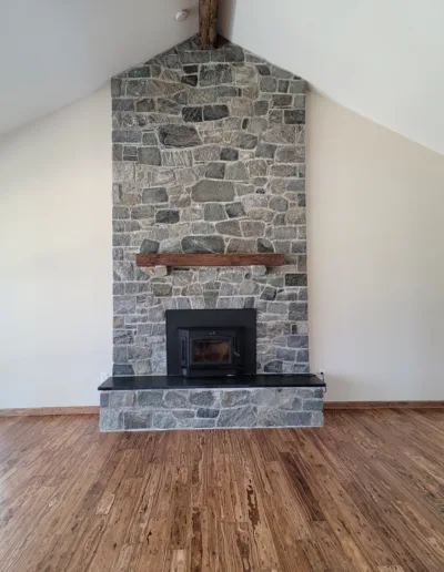 A stone fireplace in an empty living room.
