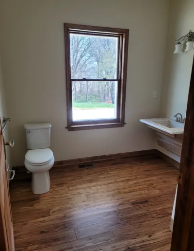 A bathroom with wood floors and a window.