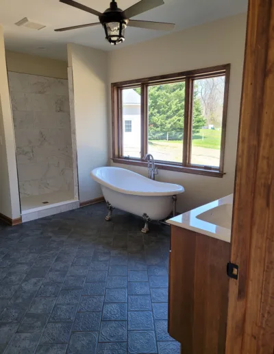A bathroom with a bathtub, sink and window.