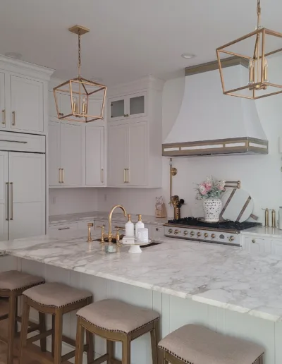 A white kitchen with marble counter tops and stools.
