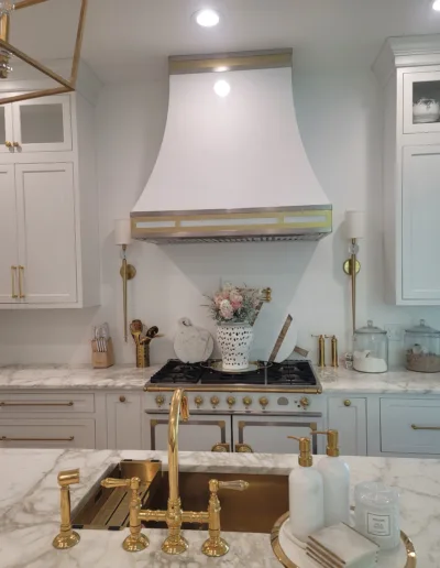 A kitchen with white cabinets and gold accents.