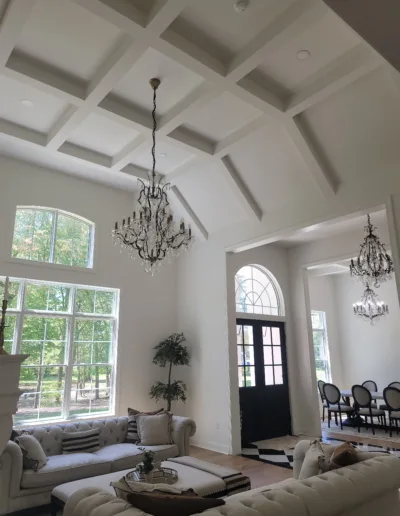 A living room with a chandelier and white furniture.