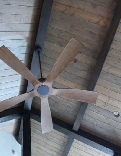 A ceiling fan with wood blades on a wooden ceiling.