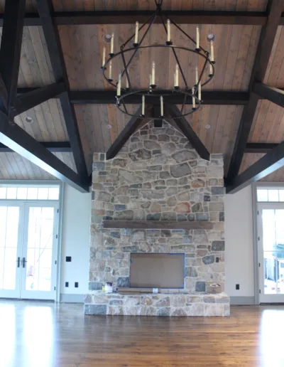 A large living room with a stone fireplace and chandelier.