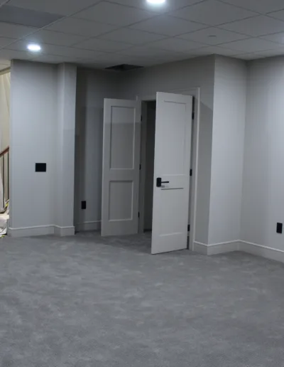A room with two doors and a gray carpet.