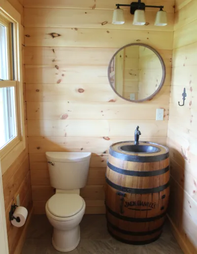 A bathroom with a toilet and a wooden barrel.