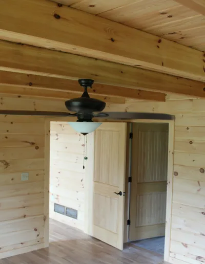 A ceiling fan in a room with wood walls.