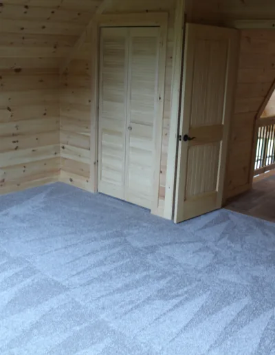 A room in a log cabin with a carpet.