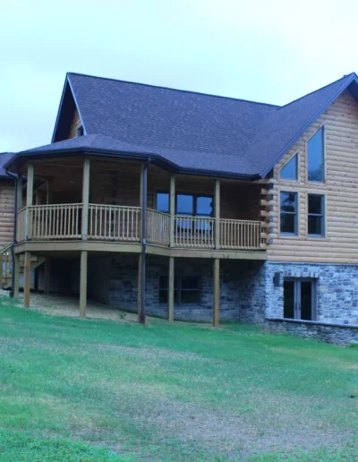 A large log home sitting on a grassy field.