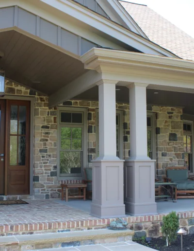 The front porch of a house with stone pillars.