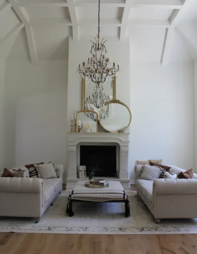 A living room with white furniture and a chandelier.