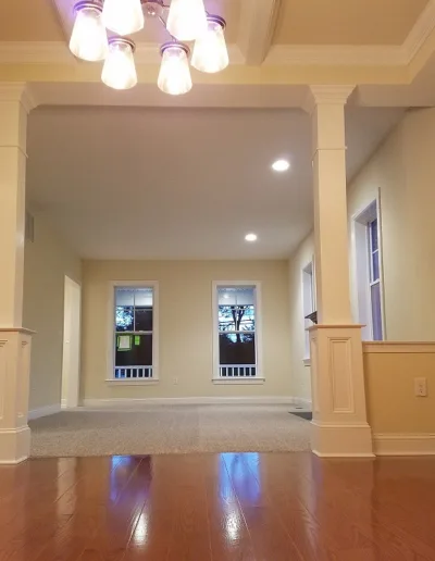 An empty living room with hardwood floors and a chandelier.